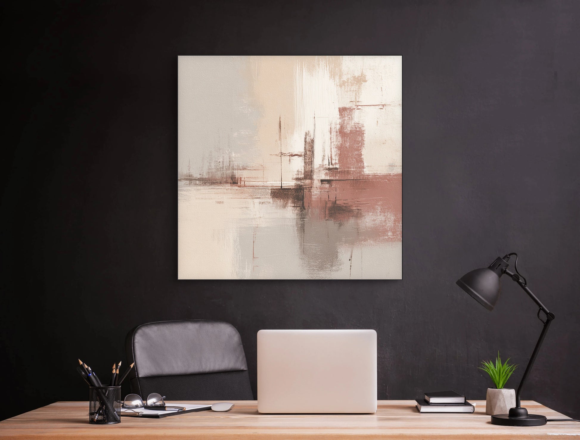 Abstract schilderij in beige en roze tinten boven een houten bureau met laptop en zwarte wandlamp
