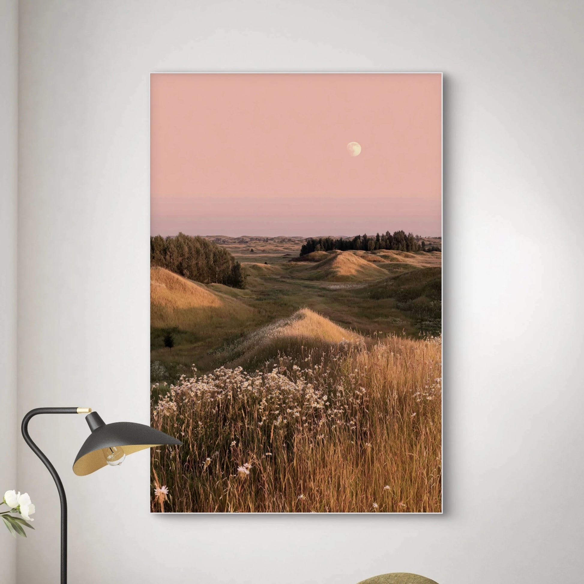 Detail van landschap met gras, bloemen en opkomende maan in roze licht
