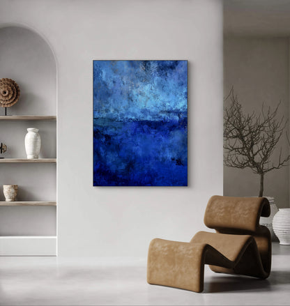Abstract blauw kunstwerk aan lichte muur in moderne woonkamer met designstoel
