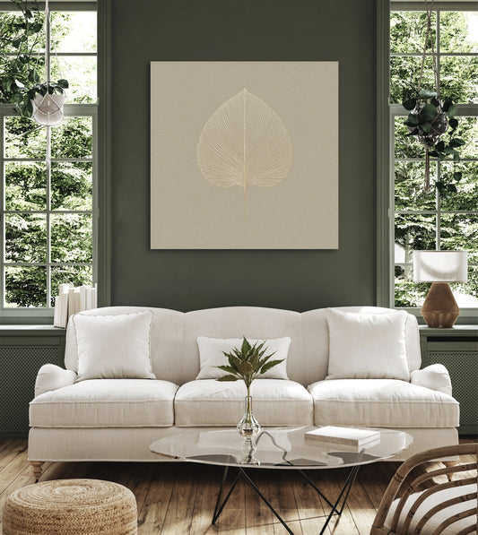 Kunstwerk Bladstilte boven een witte bank in een groene woonkamer met houten vloer.
