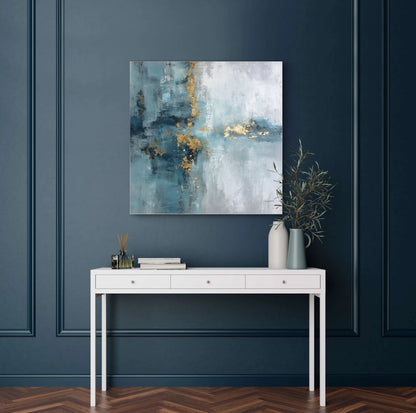 Abstract kunstwerk in blauw, grijs en goud tinten boven witte tafel tegen donkerblauwe muur
