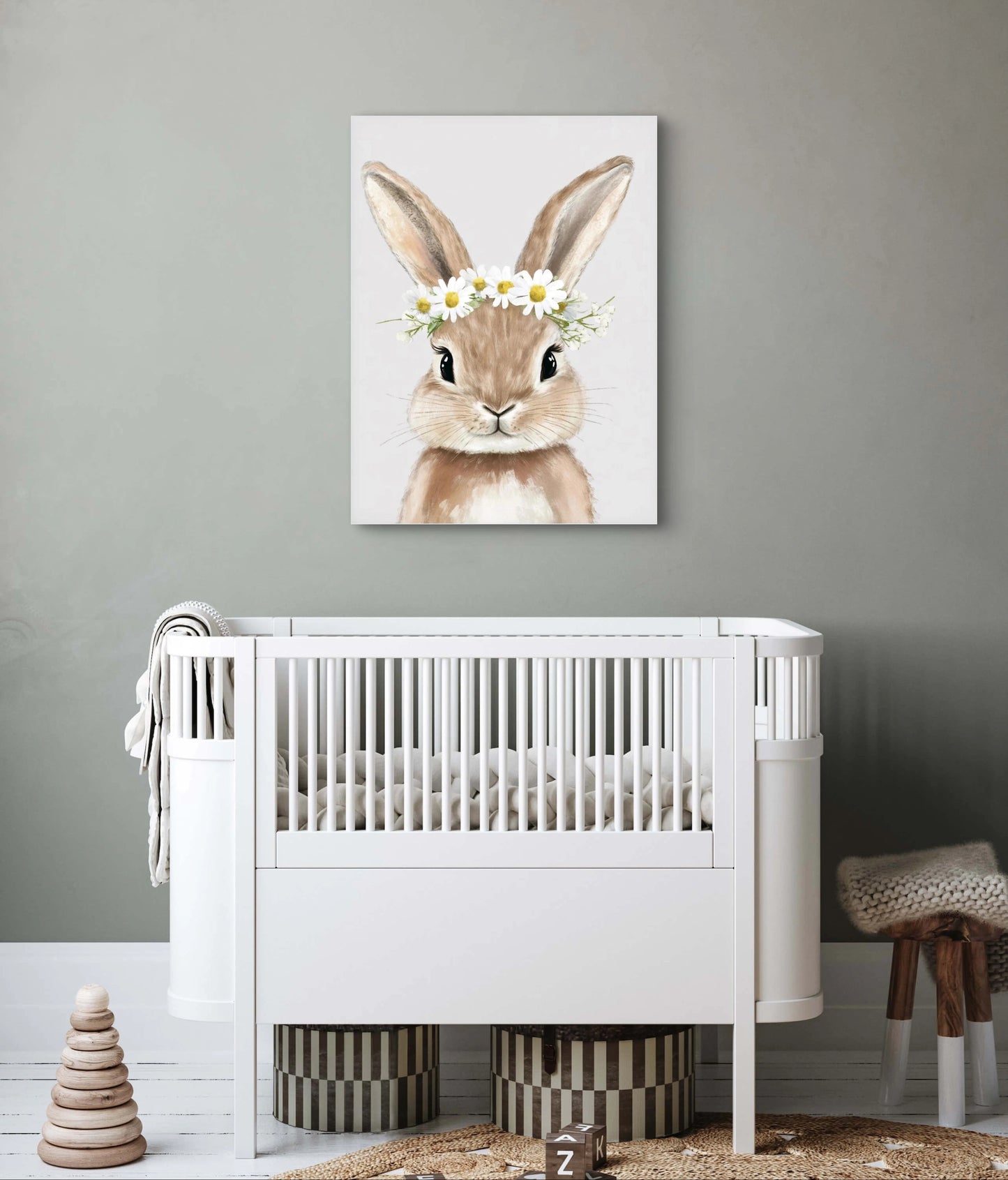Kunstwerk van konijn met bloemenkrans boven een wit babybedje in neutrale kinderkamer met grijze muur