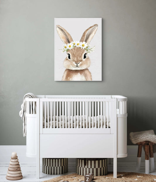 Kunstwerk van konijn met bloemenkrans boven een wit babybedje in neutrale kinderkamer met grijze muur