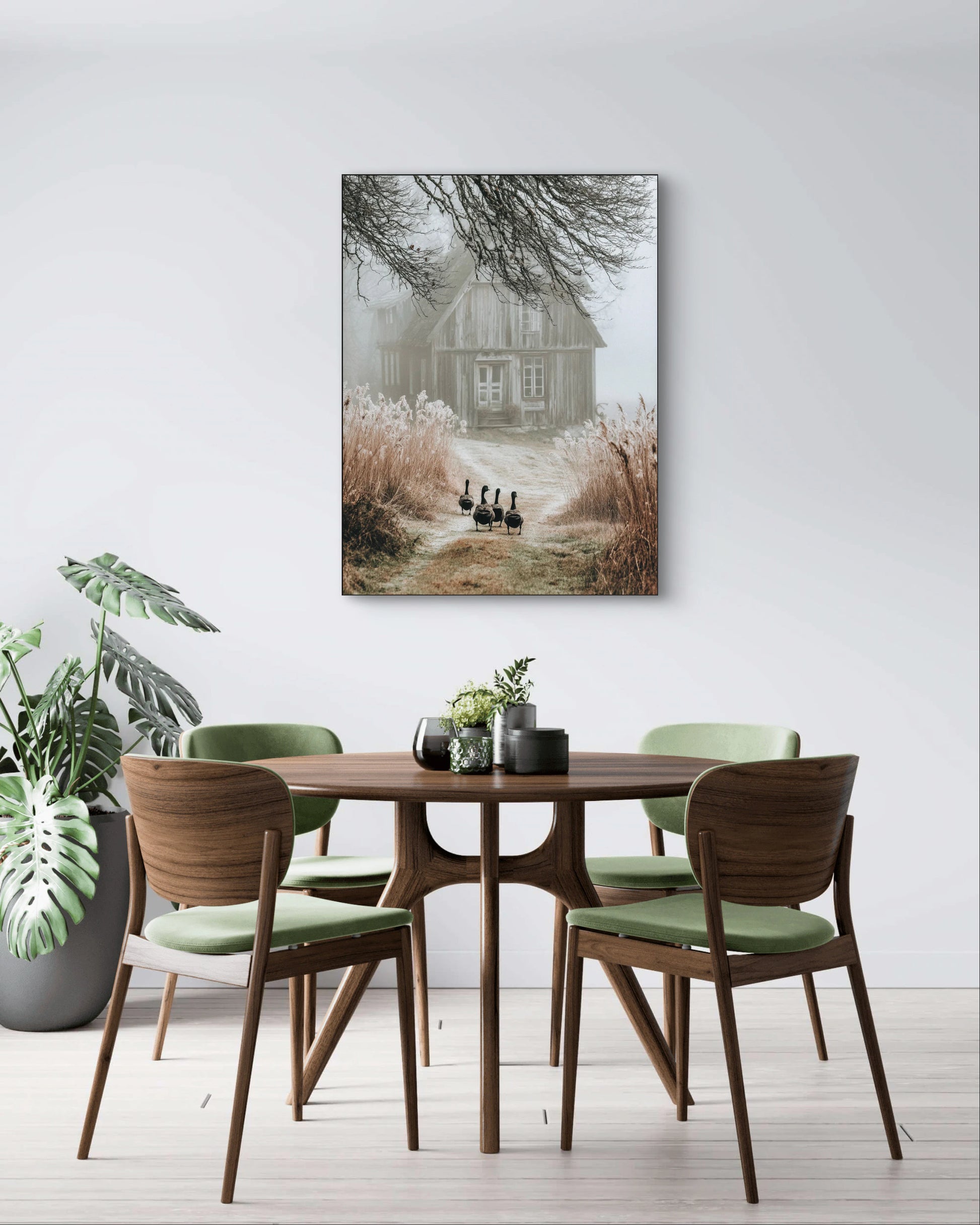 Fotokunstwerk met houten huis en ganzenpad aan de muur boven een ronde tafel met groene stoelen