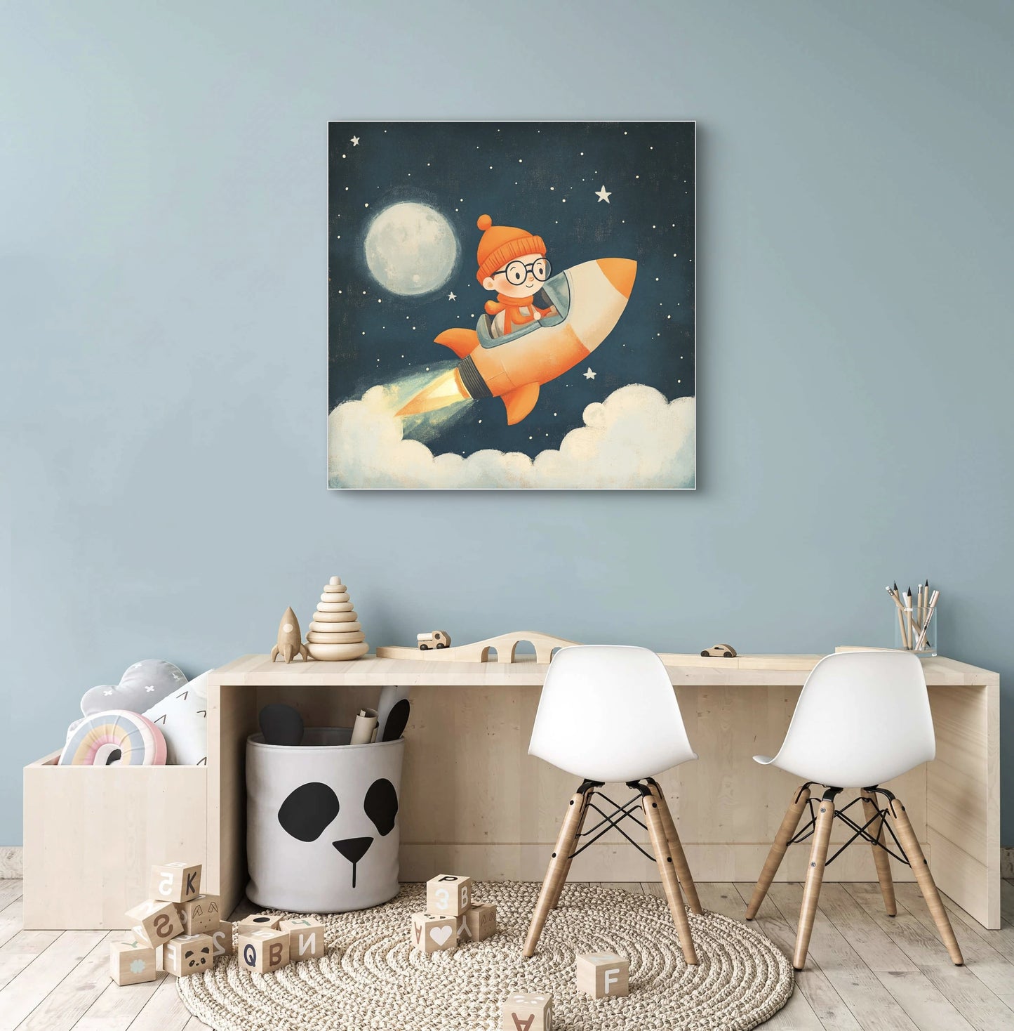 Mock-up van een kunstwerk met kind in raket aan een blauwe muur boven een houten kindertafel met stoeltjes en speelgoed.
