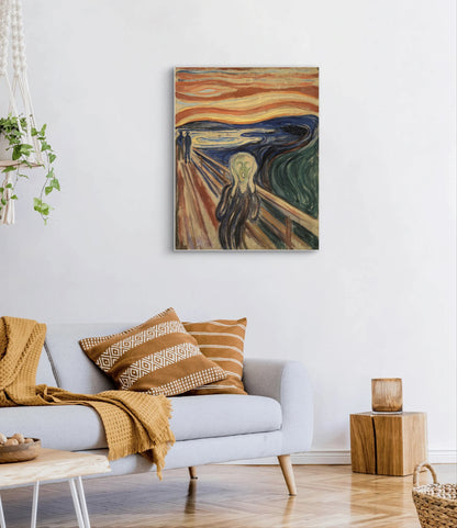 Schilderij “De Schreeuw” van Edvard Munch boven een lichtgrijze bank met okergele kussens en plaid
