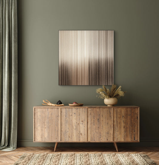 Abstract kunstwerk in brons en zand tinten boven houten dressoir met groene muur
