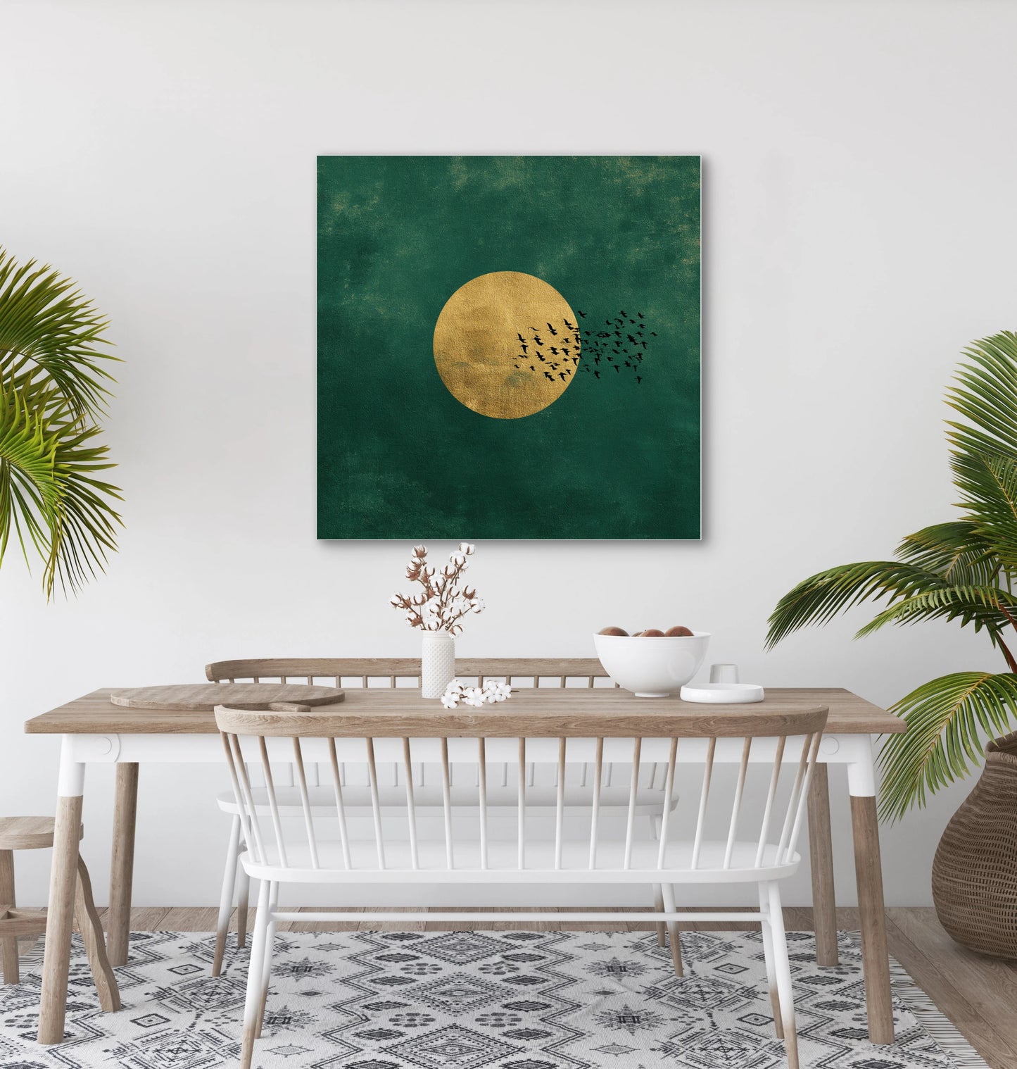 Textielkunstwerk Gouden Vlucht boven een houten eettafel met witte stoelen en groene planten.
