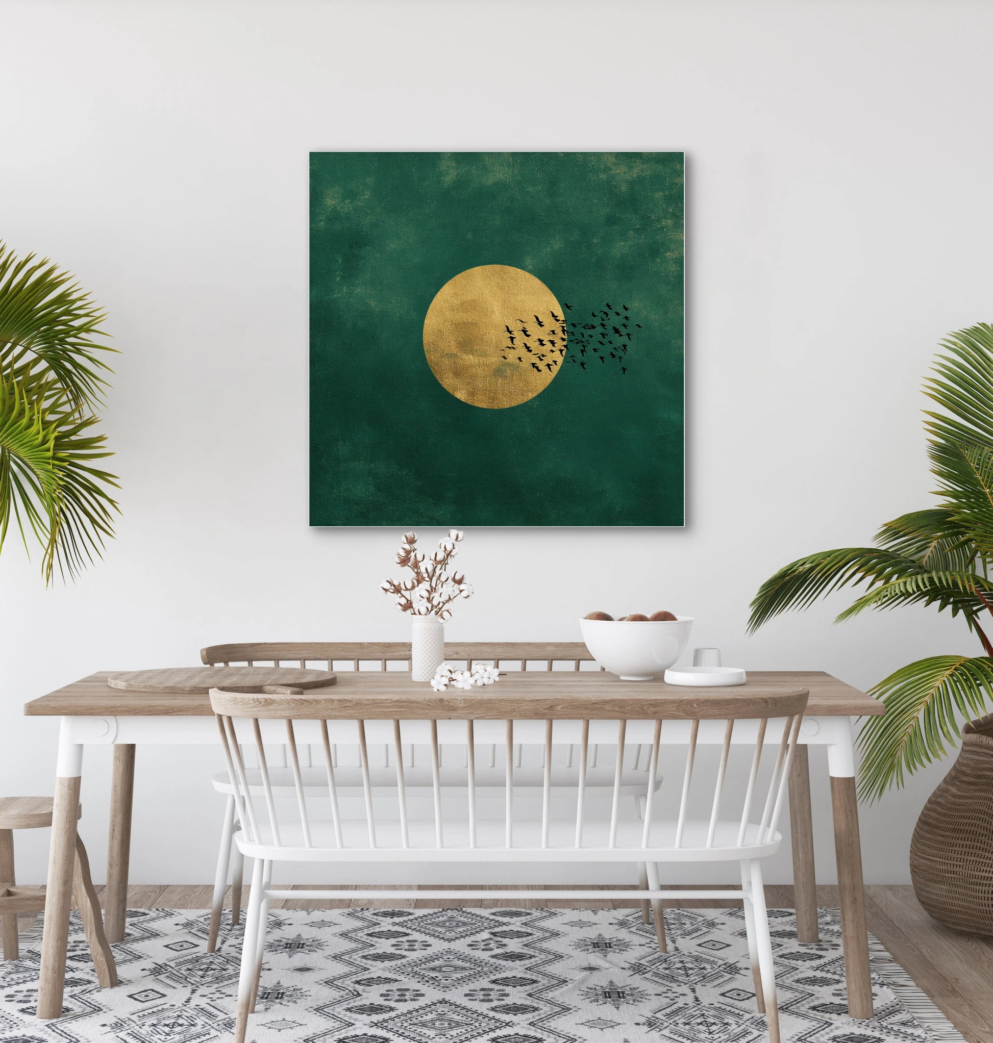 Textielkunstwerk Gouden Vlucht boven een houten eettafel met witte stoelen en groene planten.
