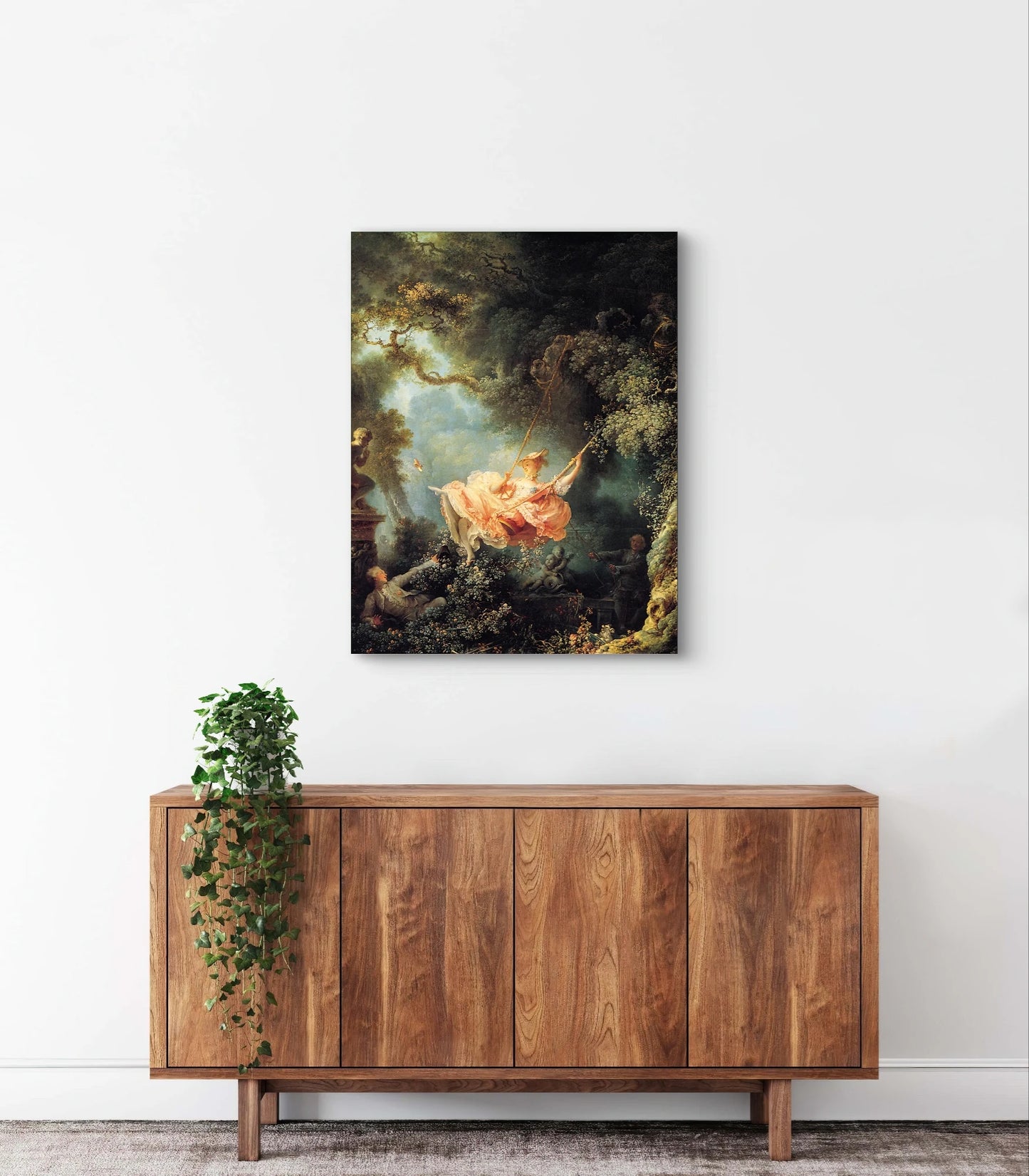 De Schommel van Fragonard boven een houten kast met hangplant tegen een witte muur
