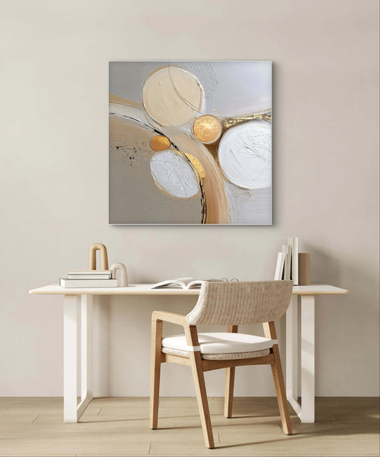 Abstract kunstwerk in goud, beige en wit tonen boven bureau met houten stoel
