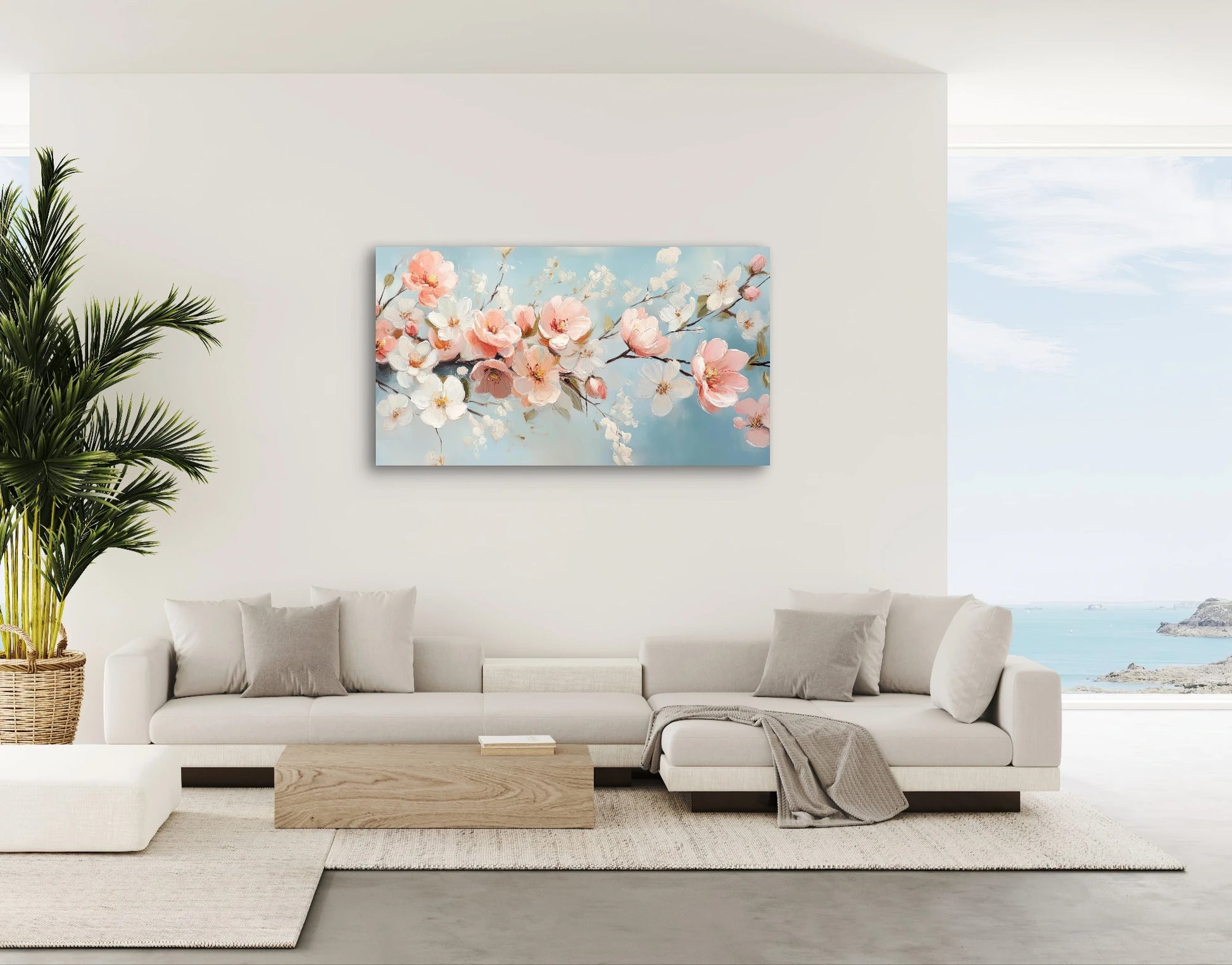 Textielkunstwerk met pastelblauwe achtergrond en bloesems in wit, roze en perzik, hangend boven lichte hoekbank in zonnige woonkamer
