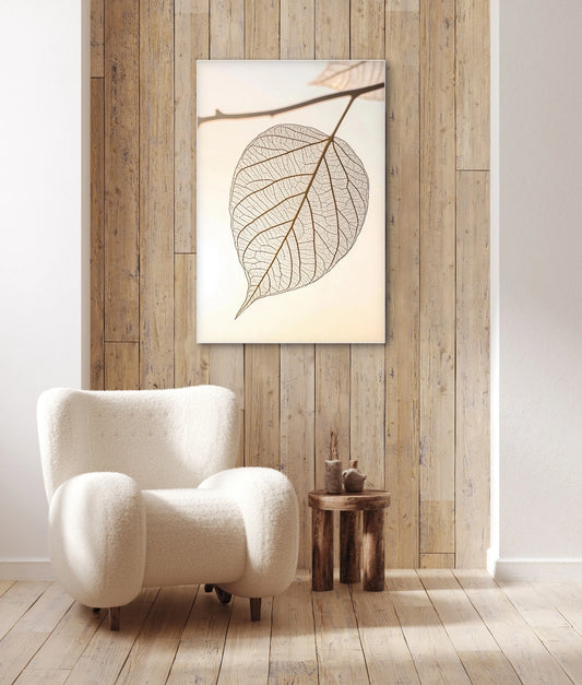 Wandkunst met transparant blad in licht interieur met houten wand en witte fauteuil

