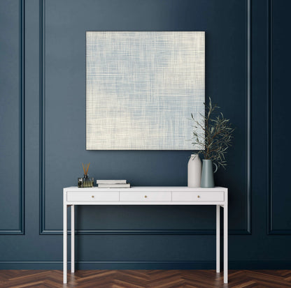 Lichtblauw geweven kunstwerk in woonkamer met donkerblauwe muur en wit console  
