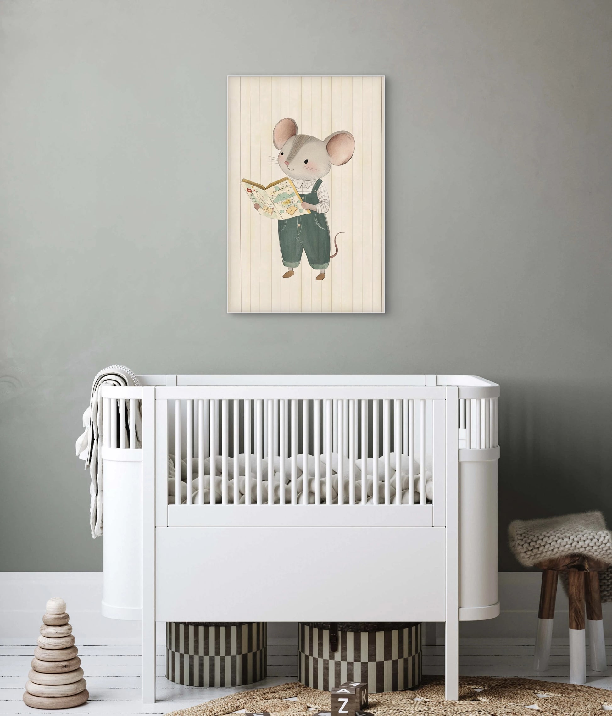 Mock-up van een babykamer met kunstwerk van een muis die een boek leest, aan een grijsgroene muur boven een wit babybedje.
