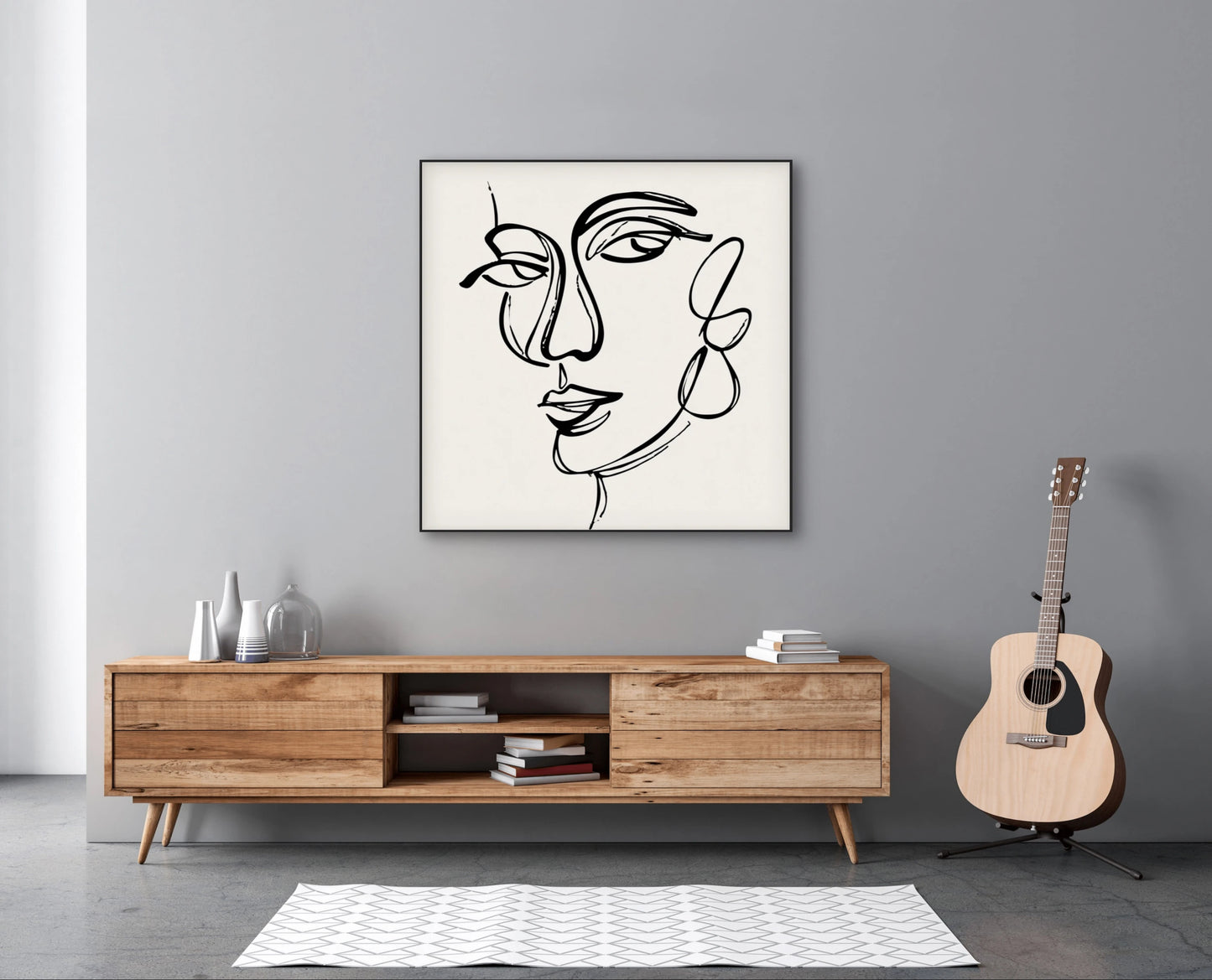 Minimalistisch lijnkunstwerk van vrouwengezicht boven houten dressoir met gitaar ernaast

