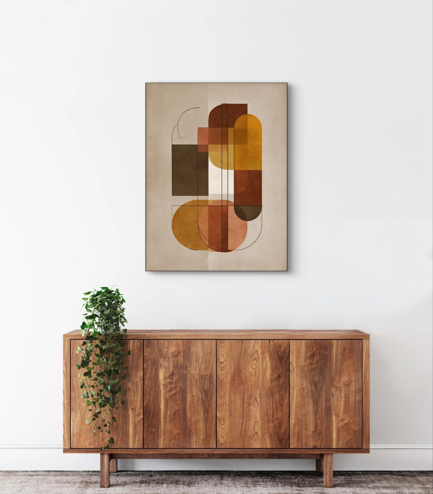 Geometrisch abstract kunstwerk in oker, bruin en terracotta aan de muur boven een houten dressoir met hangplant
