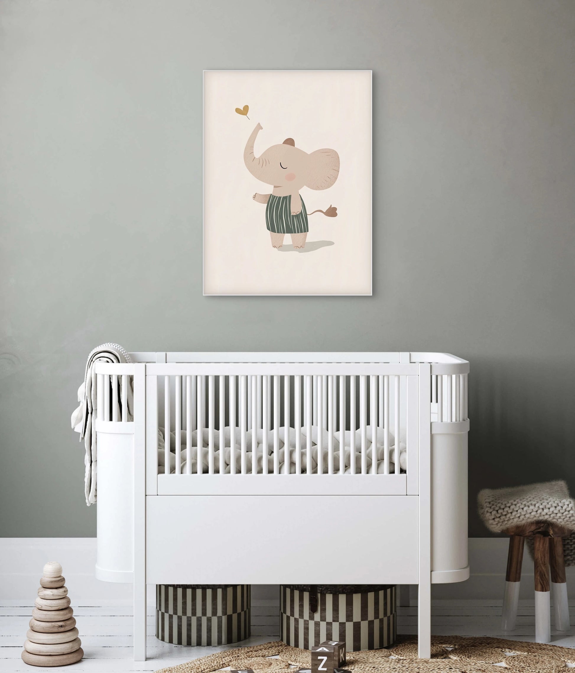 Mock-up van een babykamer met kunstwerk van een olifantje in groen pakje dat een hartje omhoog blaast, boven een wit ledikant tegen een grijsgroene muur.
