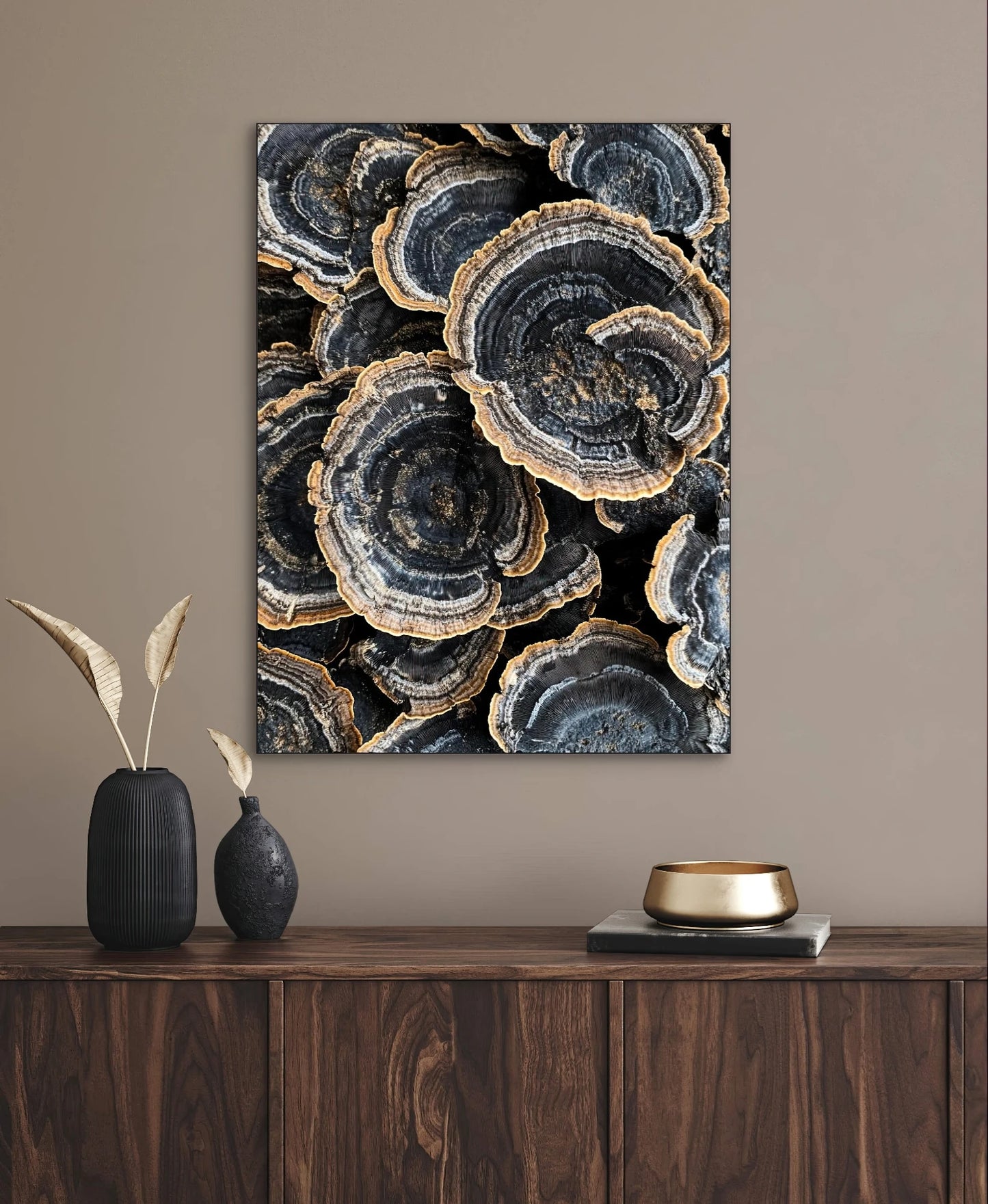 Textielkunstwerk met fossielachtige patronen in blauwgrijs en goud, hangend boven een donkerhouten kast in ton-sur-ton interieur
