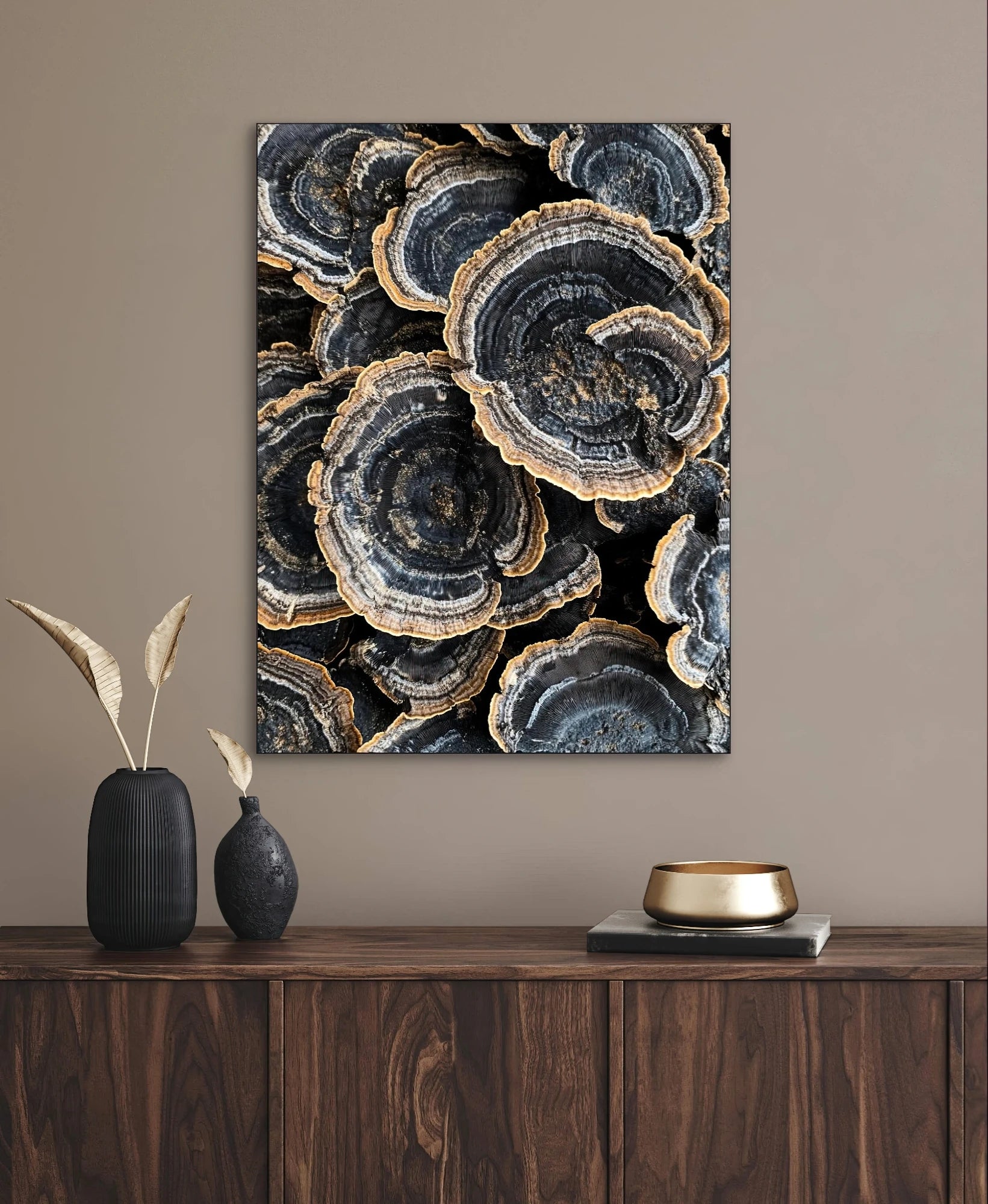 Textielkunstwerk met fossielachtige patronen in blauwgrijs en goud, hangend boven een donkerhouten kast in ton-sur-ton interieur
