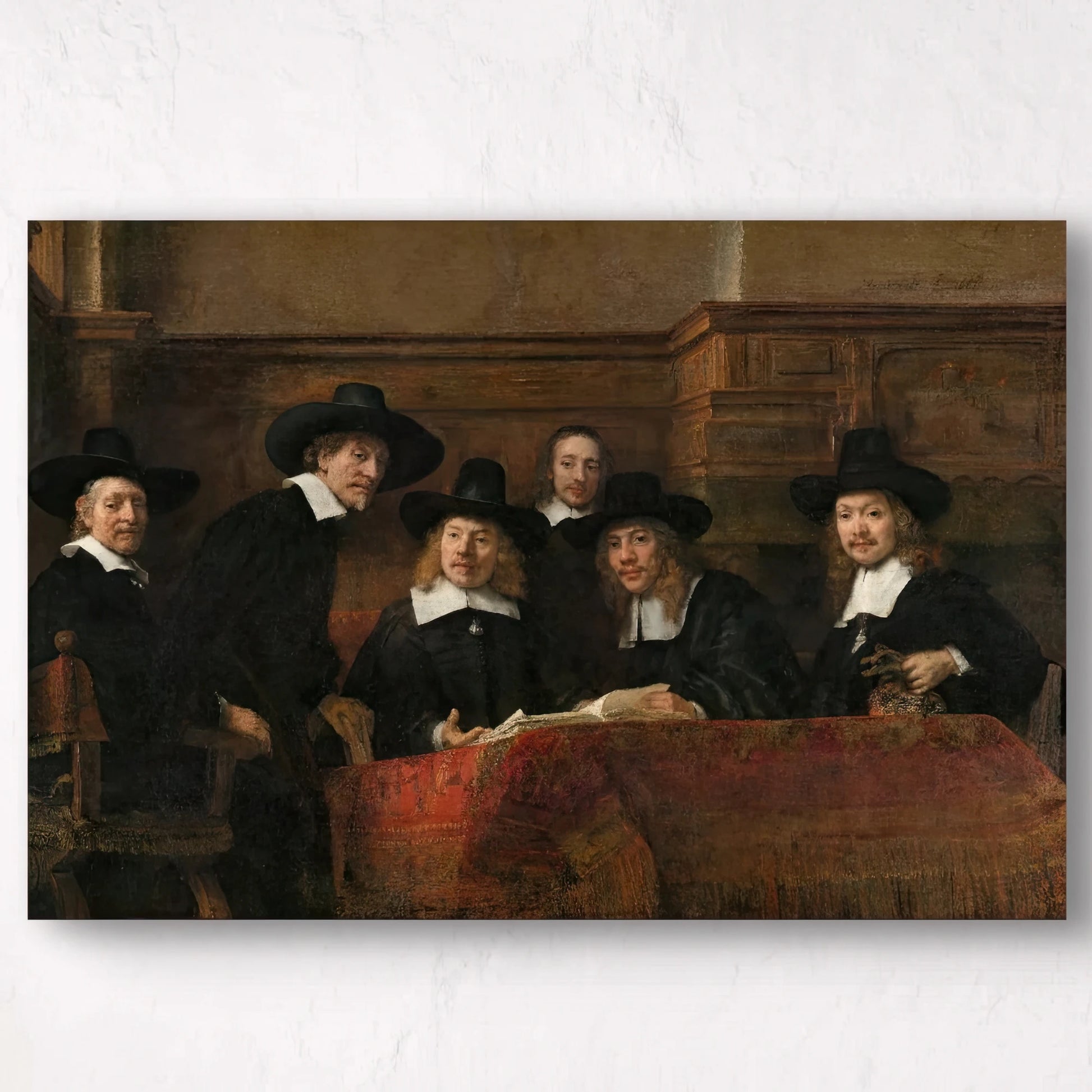 Detail van Rembrandts “De Staalmeesters” met mannen in zwarte kleding rond een tafel met tapijt

