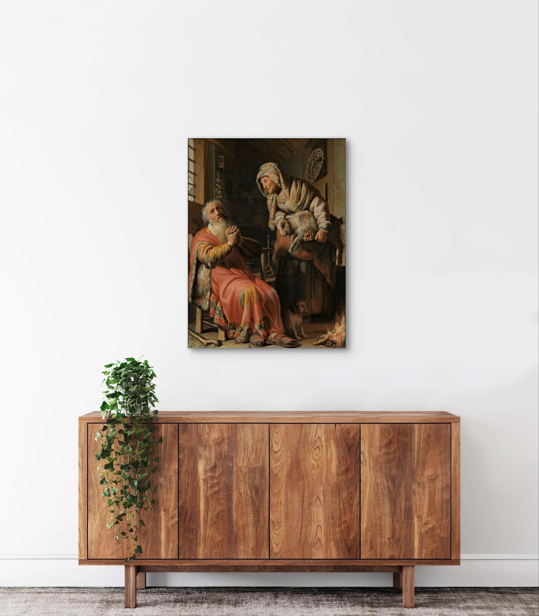 Schilderij “Tobit en Anna met het bokje” van Rembrandt boven houten dressoir in een modern, minimalistisch interieur
