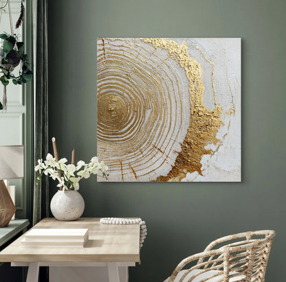 Textielkunstwerk Ringen van Goud boven een houten bureau met witte bloemen en groene muur.

