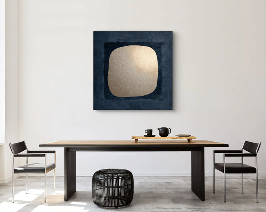 Kunstwerk Schaduw van Goud boven een houten eettafel met zwarte stoelen in een modern interieur.
