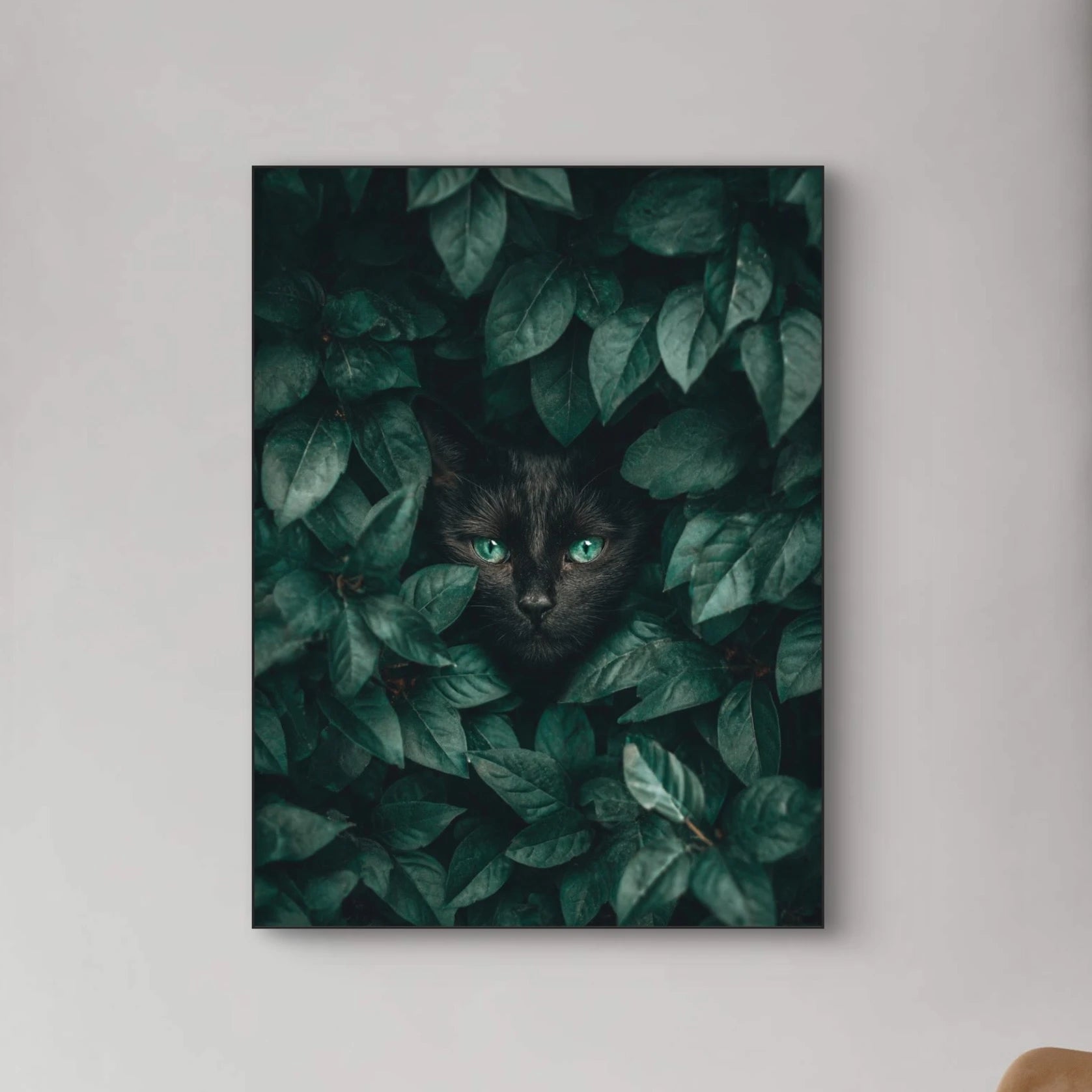 Detailopname van Schaduwblik met zwarte kat en felgroene ogen tussen bladeren  
