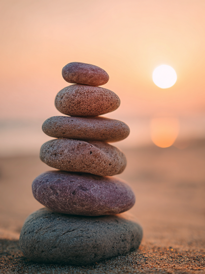 Steenbalans, minimalistisch kunstwerk met gestapelde stenen en zonsondergang
