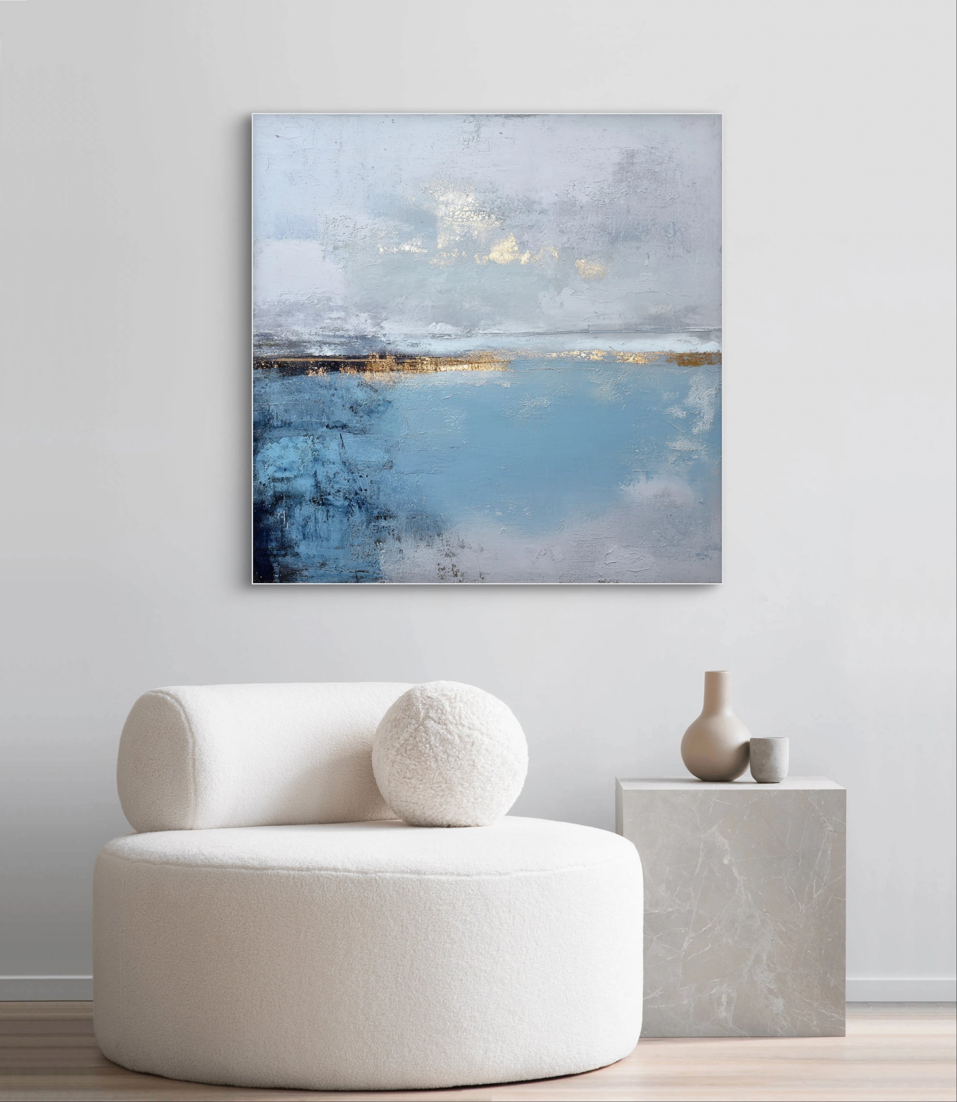 Abstract kunstwerk in blauw, wit en goud tonen boven witte stoel in modern interieur
