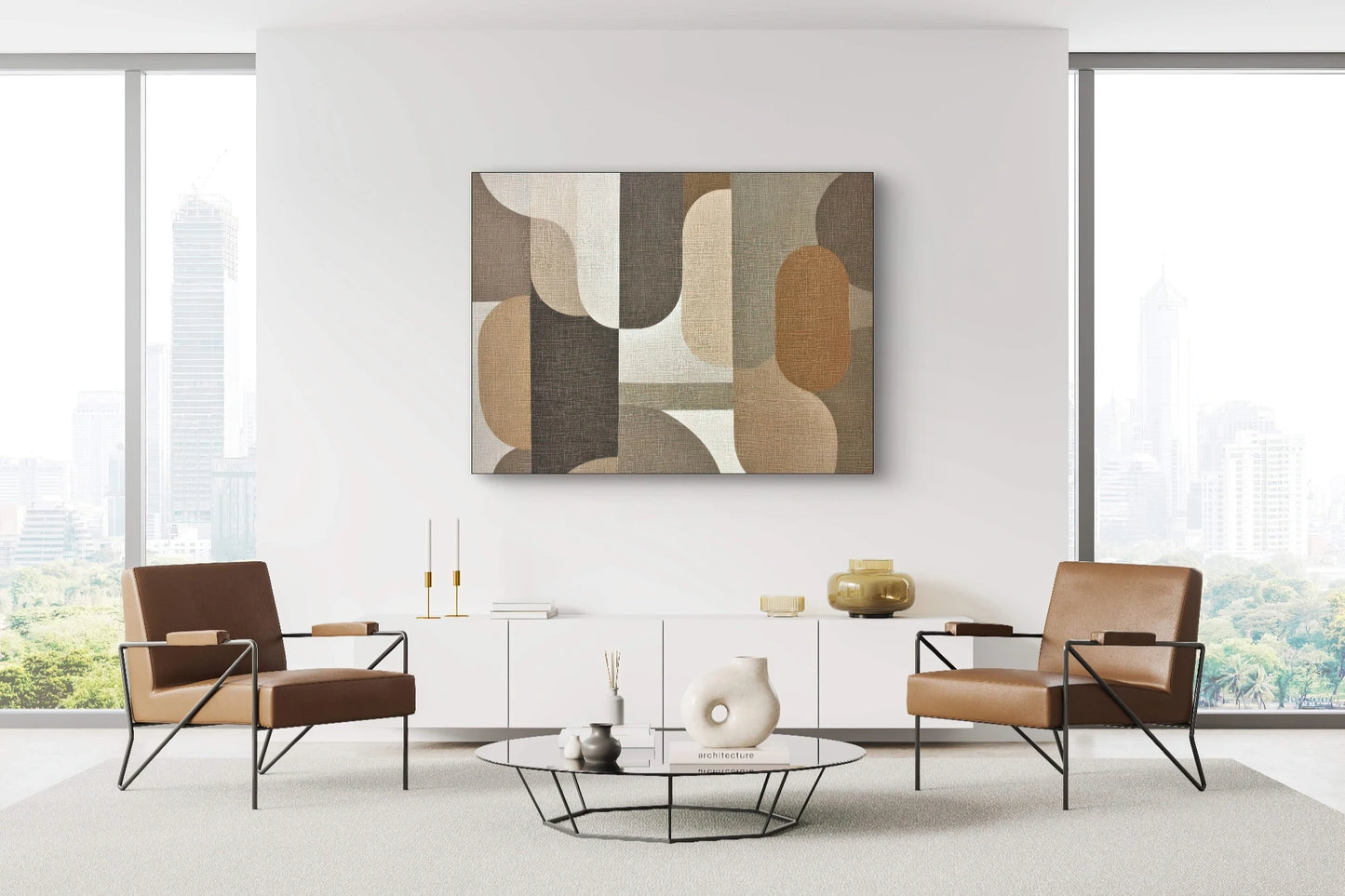 Textuurkunstwerk in aardetinten aan een witte muur boven een laag modern dressoir tussen twee leren stoelen in een licht interieur
