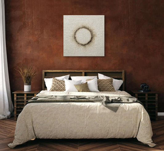 Kunstwerk Verbrand Licht boven een bed met aardetinten in een warme slaapkamer met roestbruine muur.
