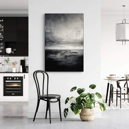 Abstract kunstwerk in zwart en grijs tonen boven zwarte stoel in modern interieur
