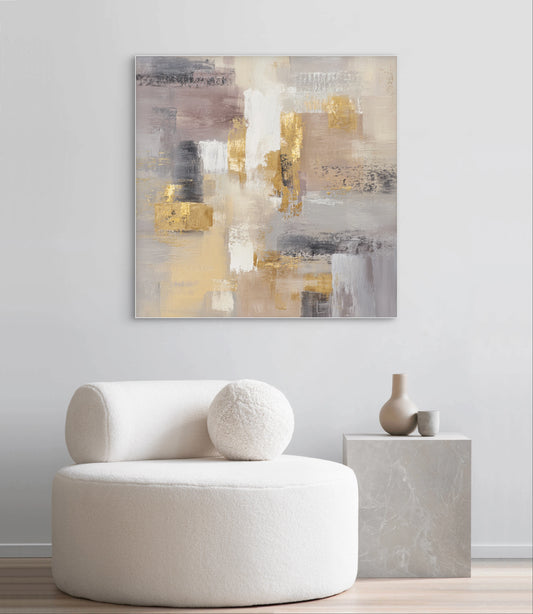 Abstract schilderij in warme beige, grijze en gouden tinten aan de muur boven een ronde witte stoel
