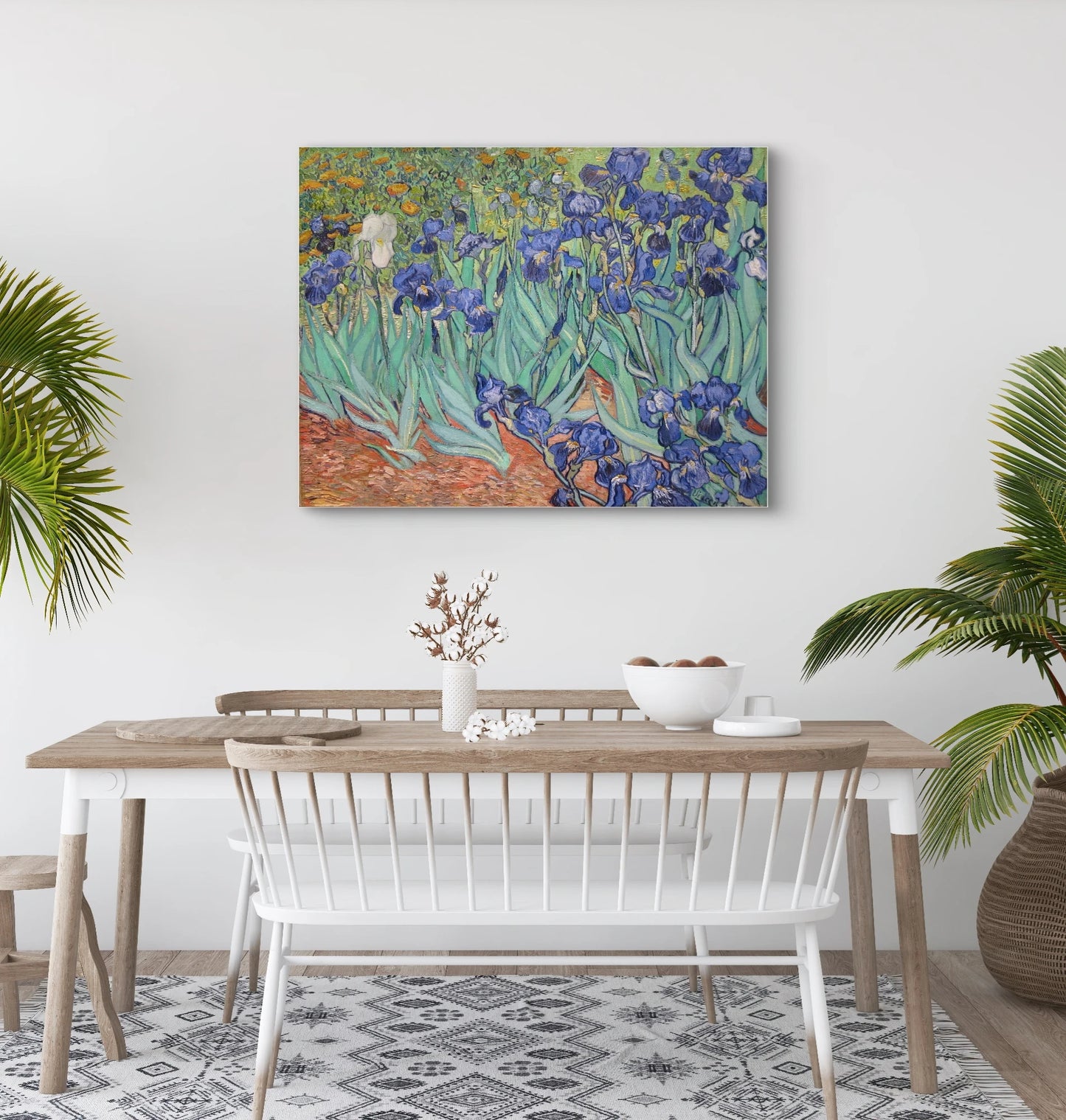 Schilderij “Irissen” van Van Gogh boven houten eettafel met witte stoelen en palmen in lichte eetkamer
