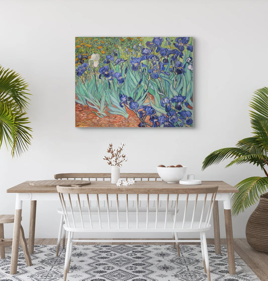 Schilderij “Irissen” van Van Gogh boven houten eettafel met witte stoelen en palmen in lichte eetkamer
