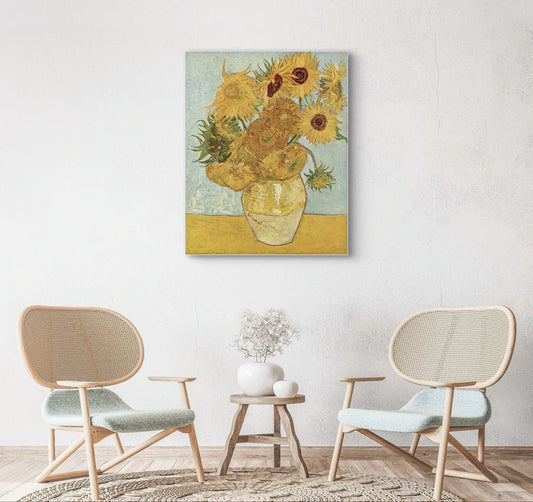 Schilderij “Zonnebloemen” van Van Gogh boven lichte stoelen en houten tafeltje in sereen interieur
