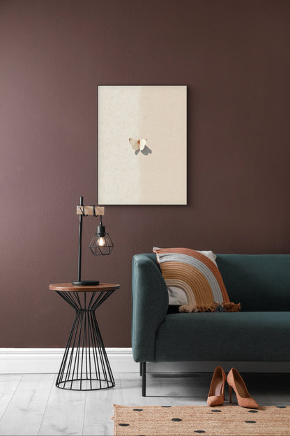 Textielkunstwerk Vlinderschaduw boven een groene bank met bruin kussen in een modern interieur.
