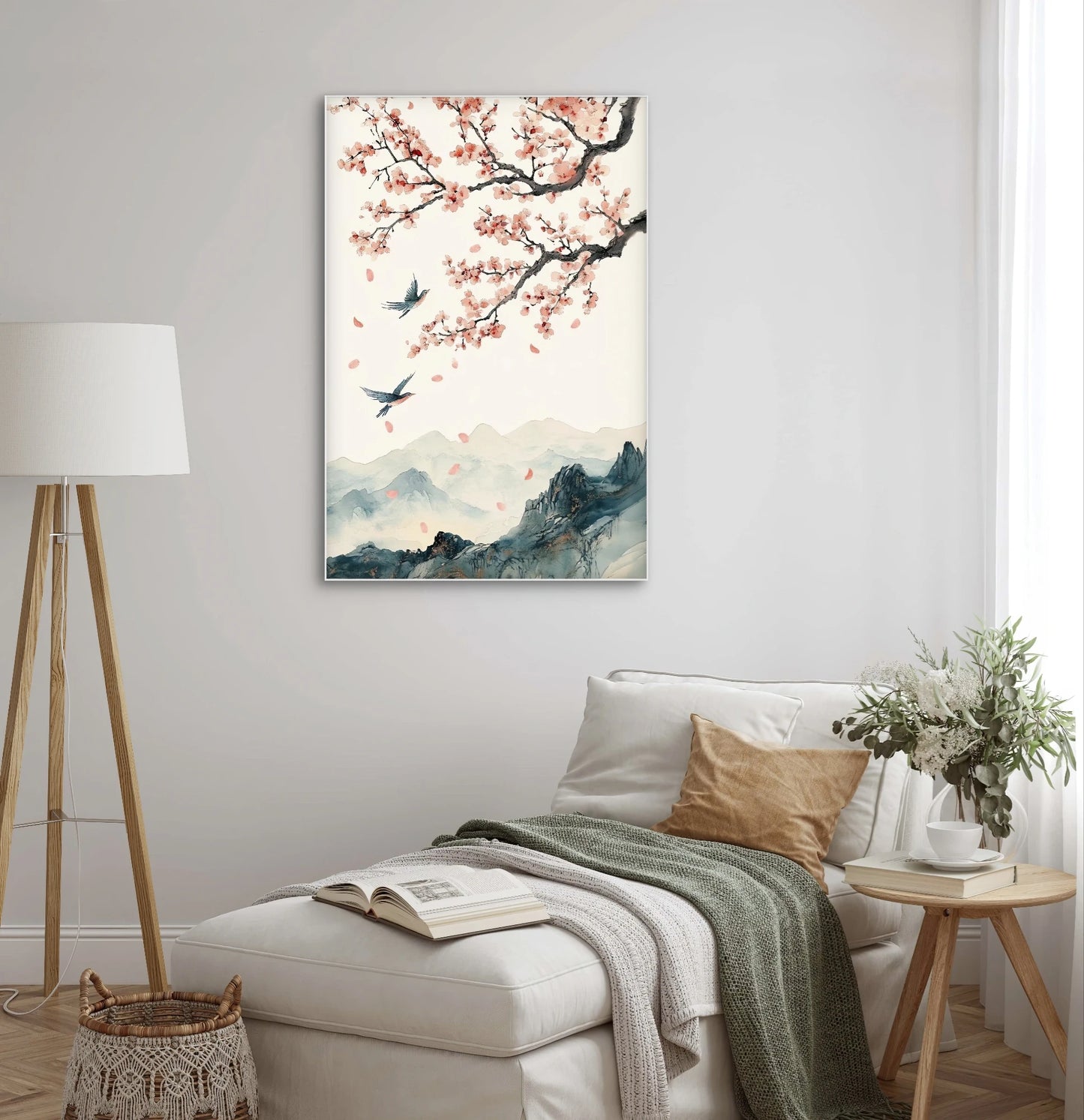 Textielkunstwerk met Oosters landschap, bloesemtak en vliegende vogels, hangend boven een witte loungefauteuil met dekens
