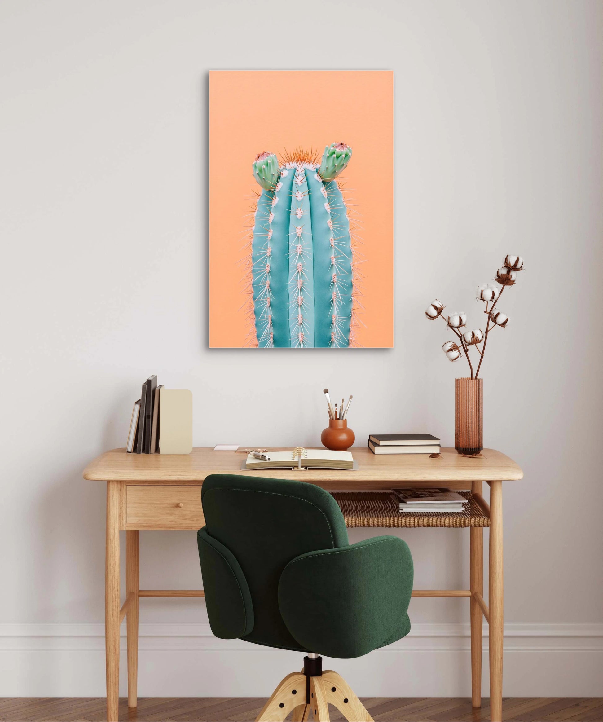 Textielkunstwerk van een blauwe cactus met bloemen aan de muur boven een houten bureau in warm interieur