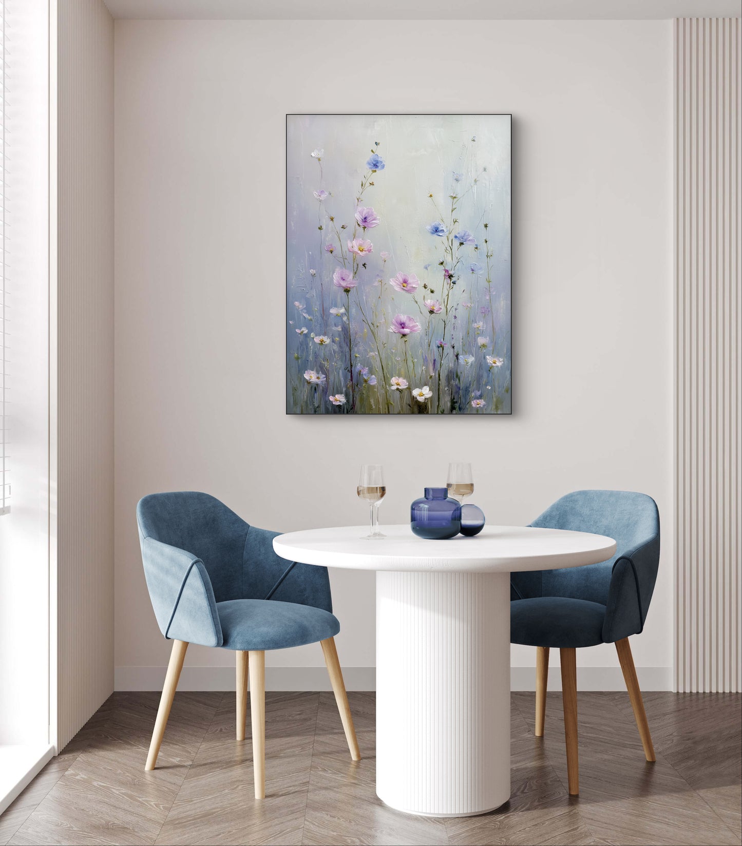 Bloemrijk kunstwerk in blauwe en roze tinten boven een ronde witte tafel met twee blauwe stoelen
