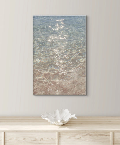 Fotografisch kunstwerk van glinsterend water aan de muur boven een houten dressoir met wit keramisch object
